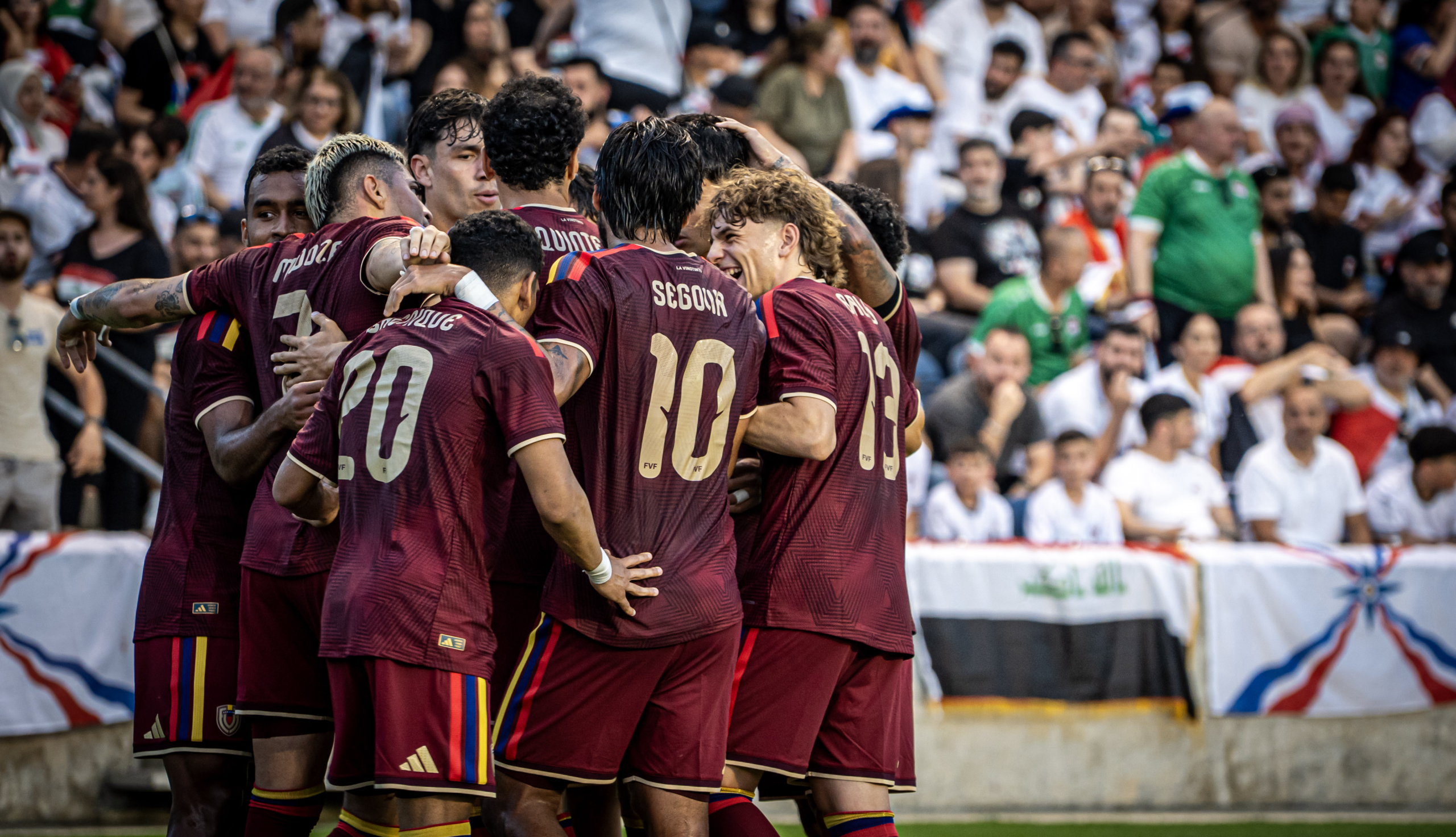 Soccer team celebrates together after scoring a goal in front of the crowd.