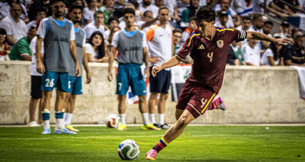 Soccer player kicks the ball during a match with spectators watching.