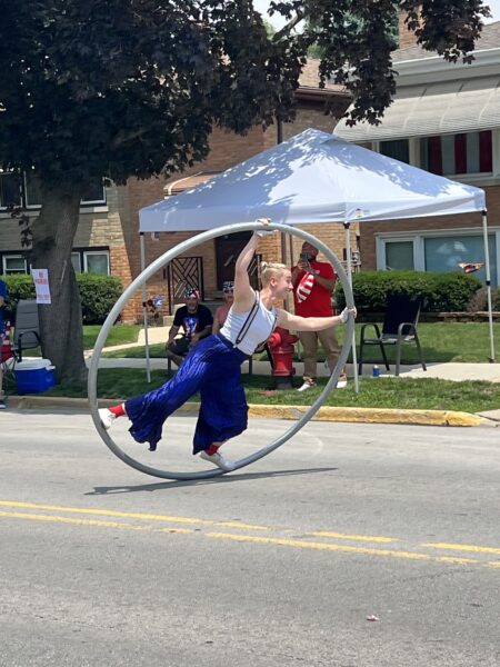 Performer balances inside a Cyr wheel during a Fourth of July parade