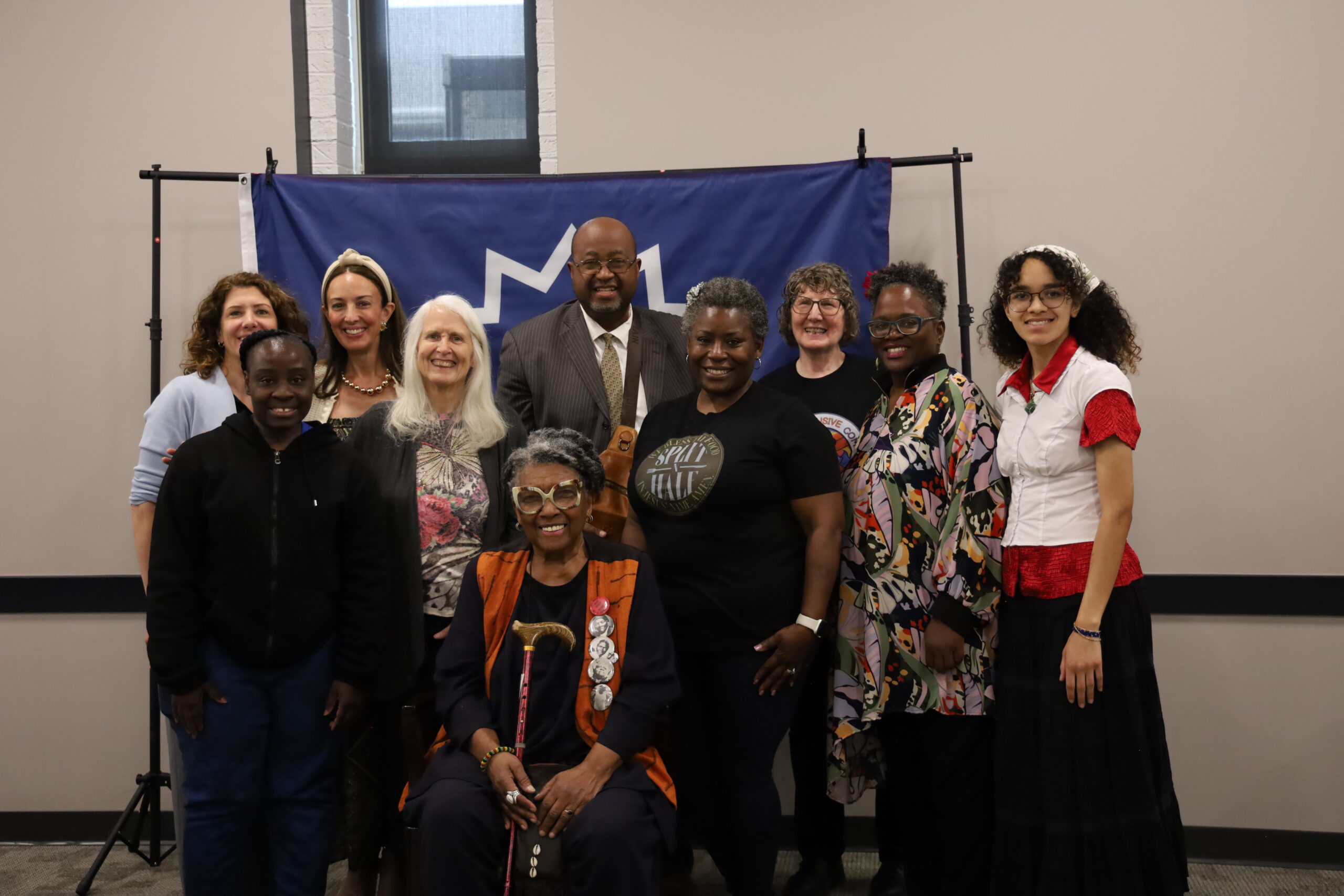 Group of community members posing for a photo at a Juneteenth event in front of a blue backdrop.