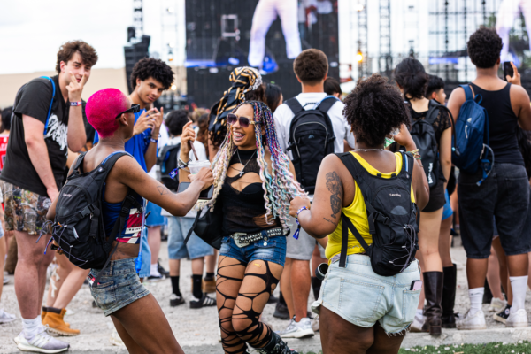 Music festival attendees dancing and socializing near the main stage during a set, surrounded by a crowd.