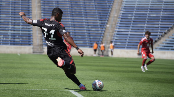 Red Bull New York Player in a black jersey prepares to kick a soccer ball with his right foot in the air.
